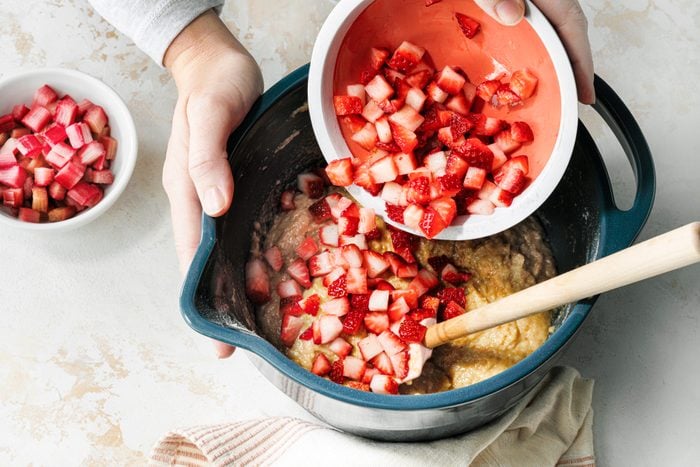 A person is mixing strawberries in a bowl.