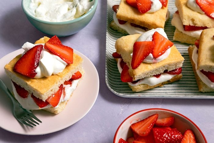 A tray of delicious strawberry shortcake topped with fresh strawberries and whipped cream on the side