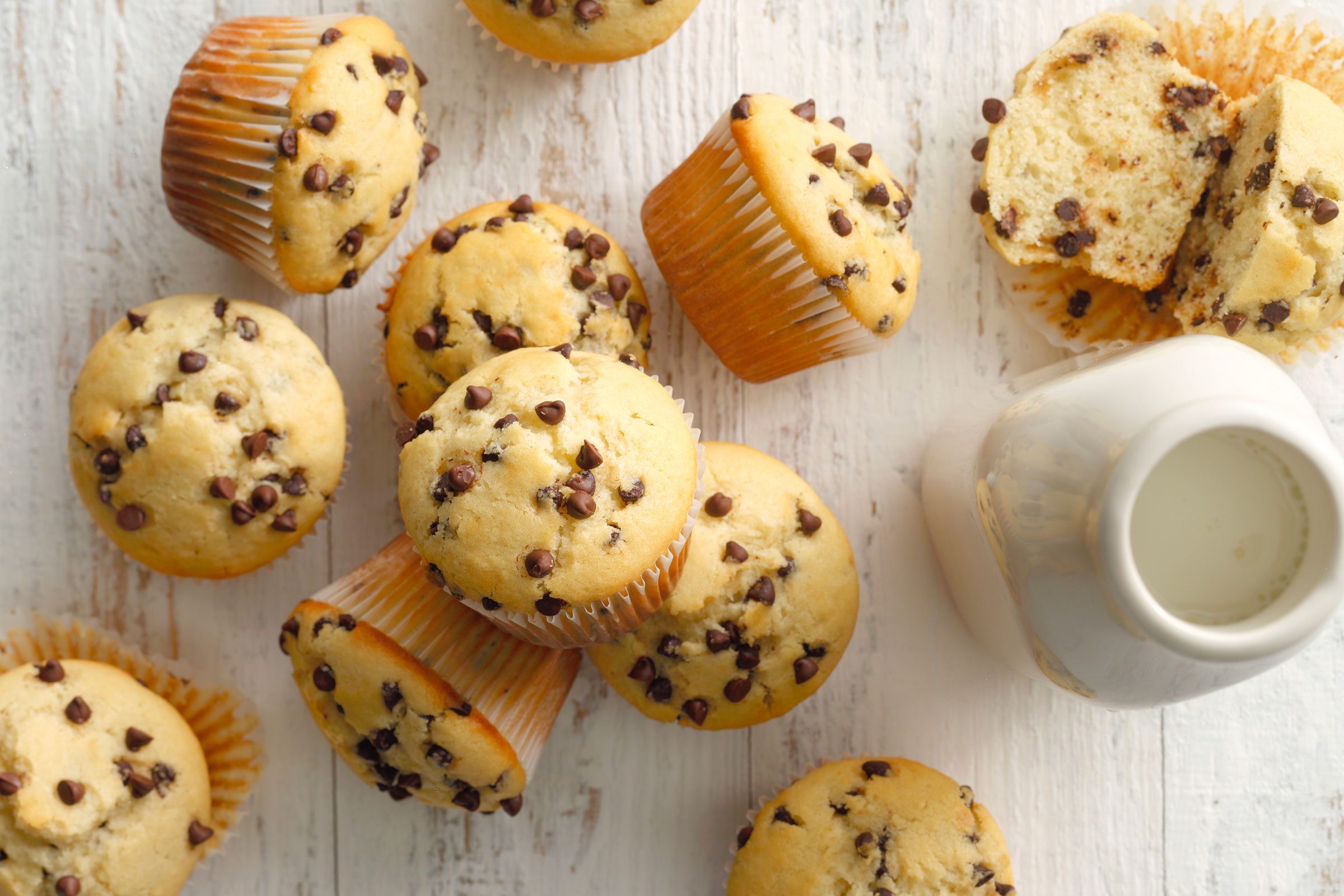 Chocolate Chip Muffins on a white wooden table with a pitcher of milk
