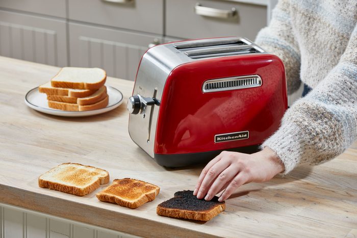 A Woman Using Kitchenaid Toaster on Wooden Kitchen Countertop