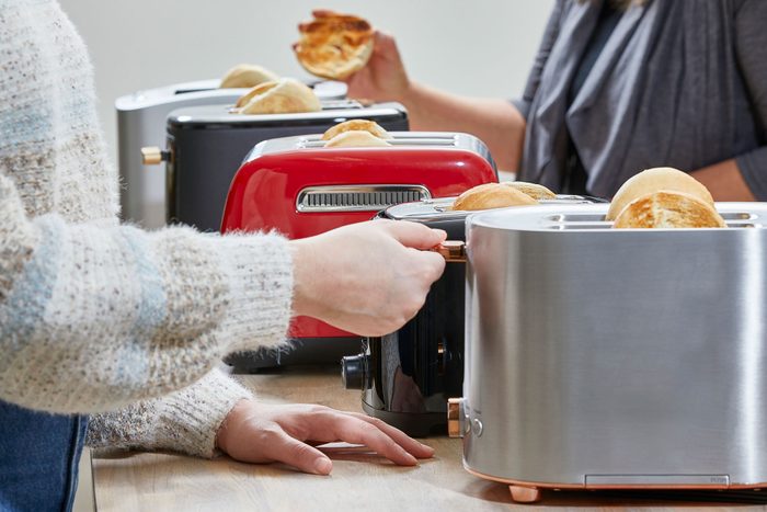 A Woman Using Café Express Toaster on Wooden Kitchen Countertop