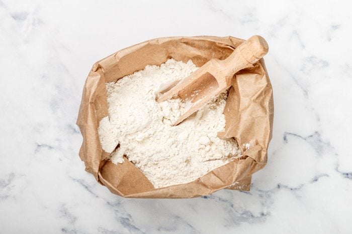 Wheat Flour And A Wooden Scoop In A Paper Bag On A Marble Table