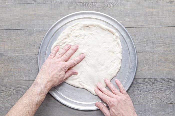 Pressing the dough on greased pan