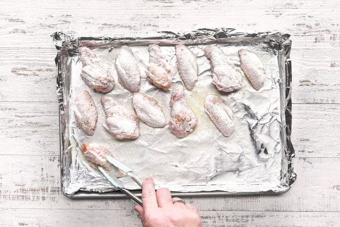 Placing chicken wings on baking sheet