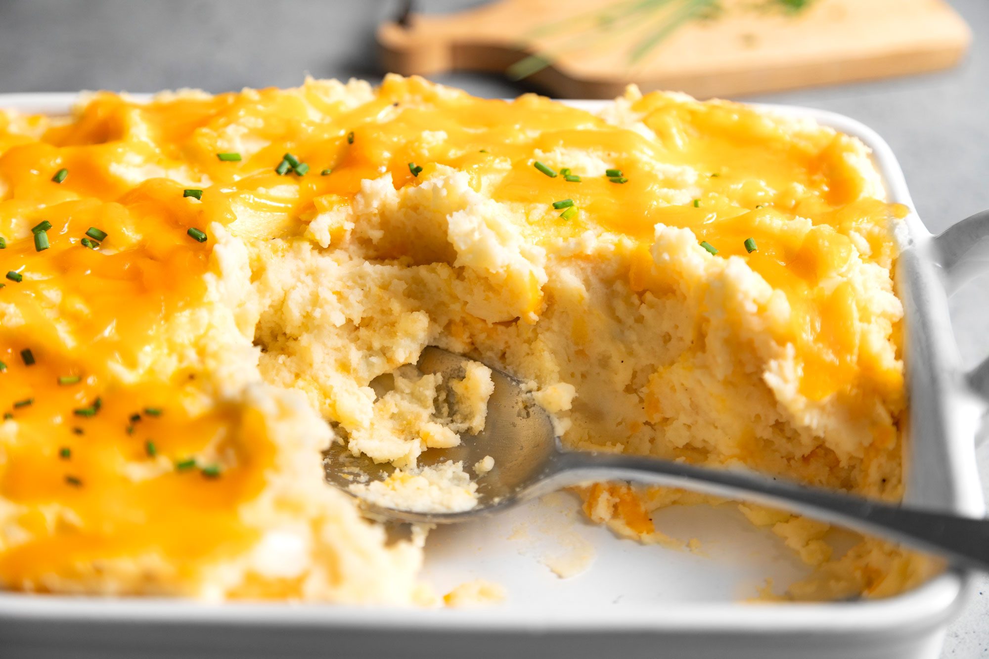 Close up shot of Cheesy Mashed Potatoes in a baking pan with spoon