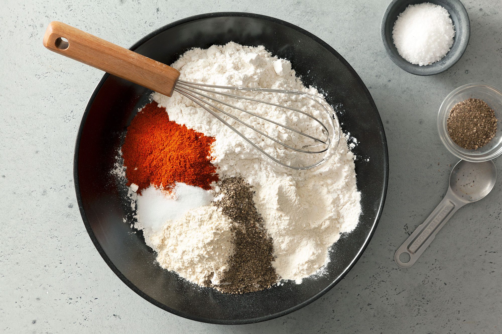 Flour, Garlic Powder, Onion Powder, Paprika, Pepper, Salt and a Whisk in a Large Mixing Bowl