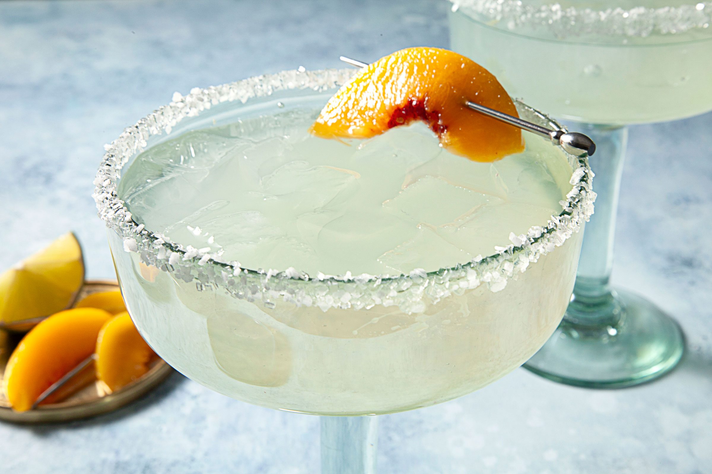 close up of salt rim margarita glass garnished with a peach and filled with peach margarita