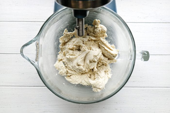 Pizza Crust Dough in a stand mixer on white painted wooden surface