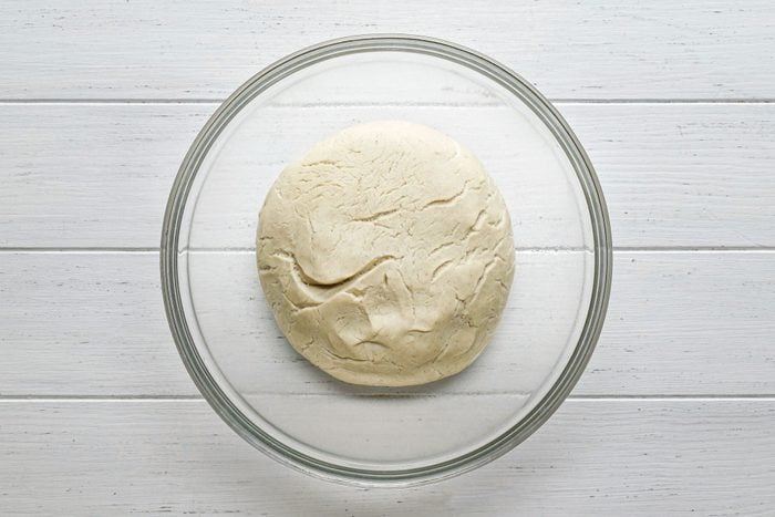 Gluten Free Pizza Crust Dough in a large glass bowl on white painted wooden surface
