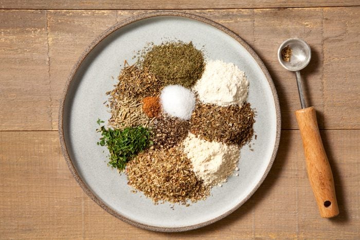 All Ingredients for Greek Seasoning placed on a ceramic plate on a wooden surface