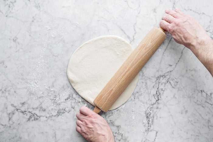 Rolling the dough with a pin on a marble countertop