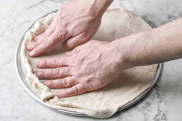 Spreading dough on a pizza pan