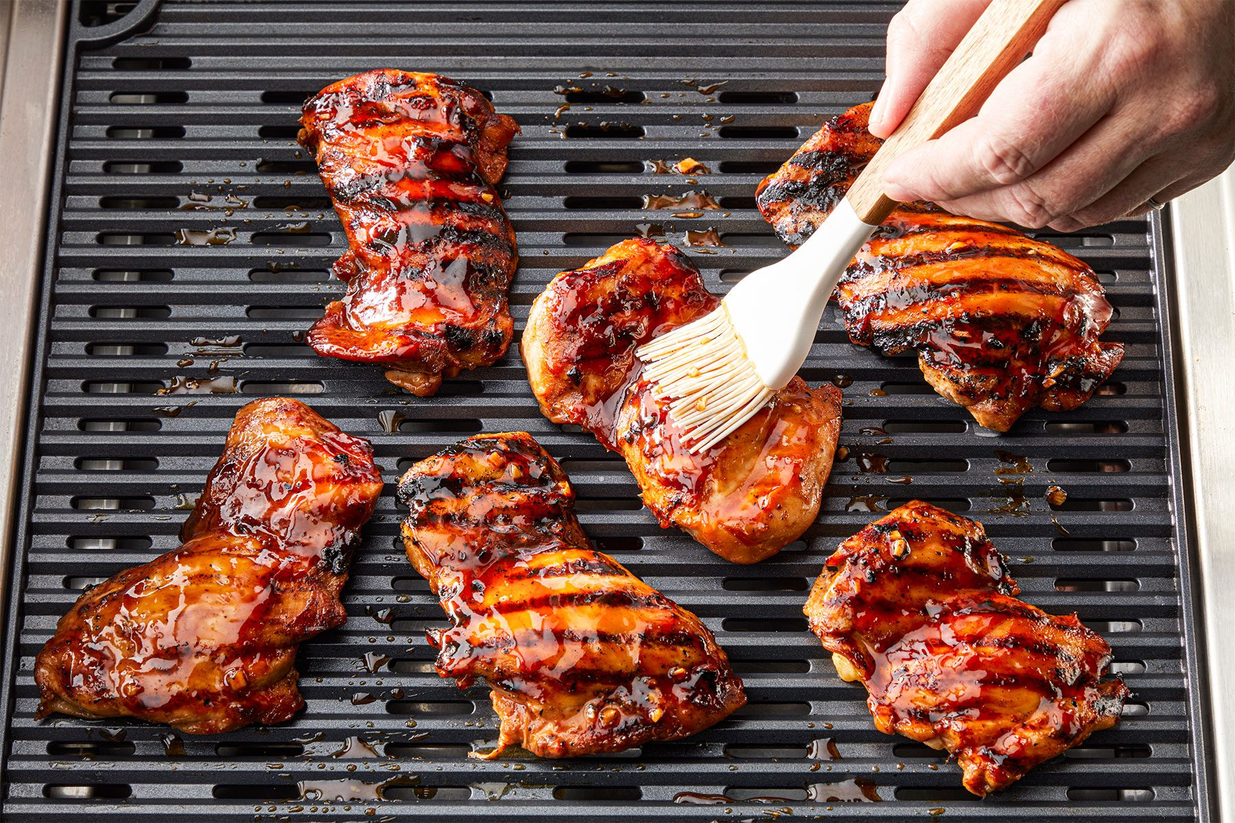 =High angle view shot of grilled chicken thighs on an oiled rack over medium heat; cook for 6-8 minutes on each side; brush butter over grill chicken;