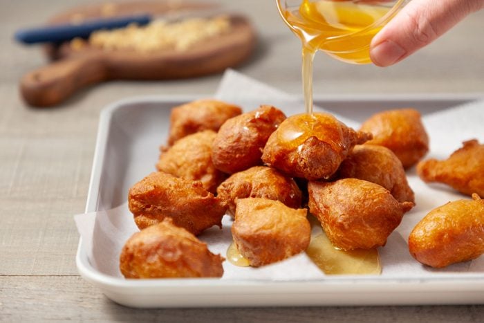 Drizzle honey syrup over the doughnut balls in a serving pan