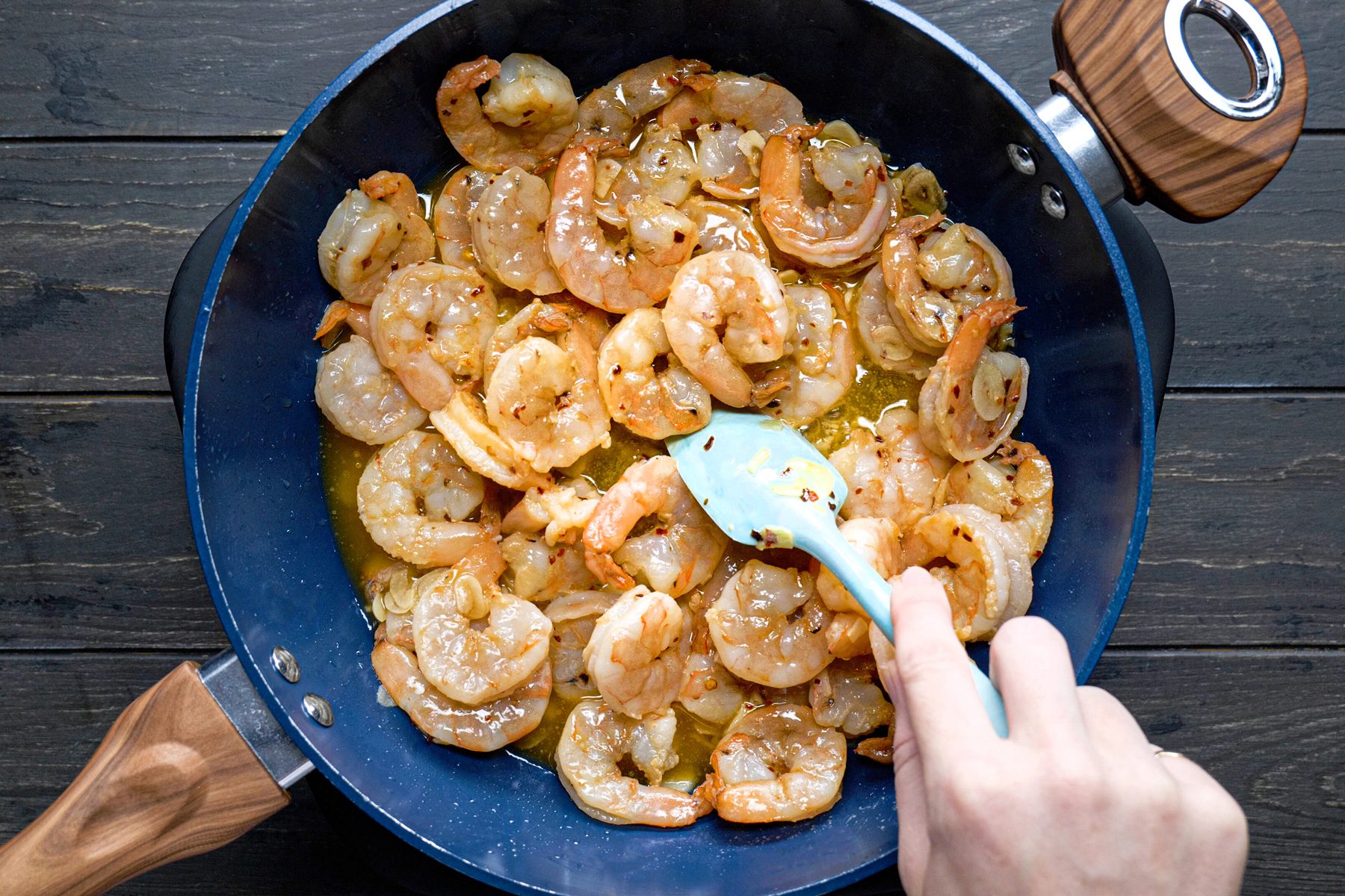 A person cooking shrimp in a large saucepan