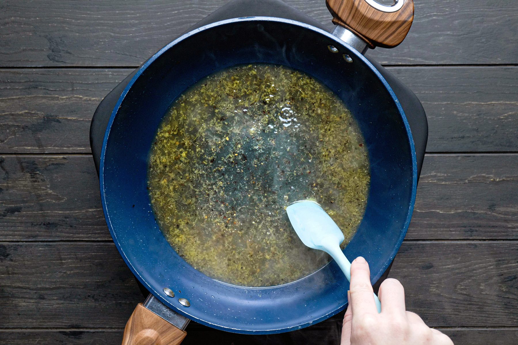A person stirring lemon juice, zest, salt and pepper in a pan