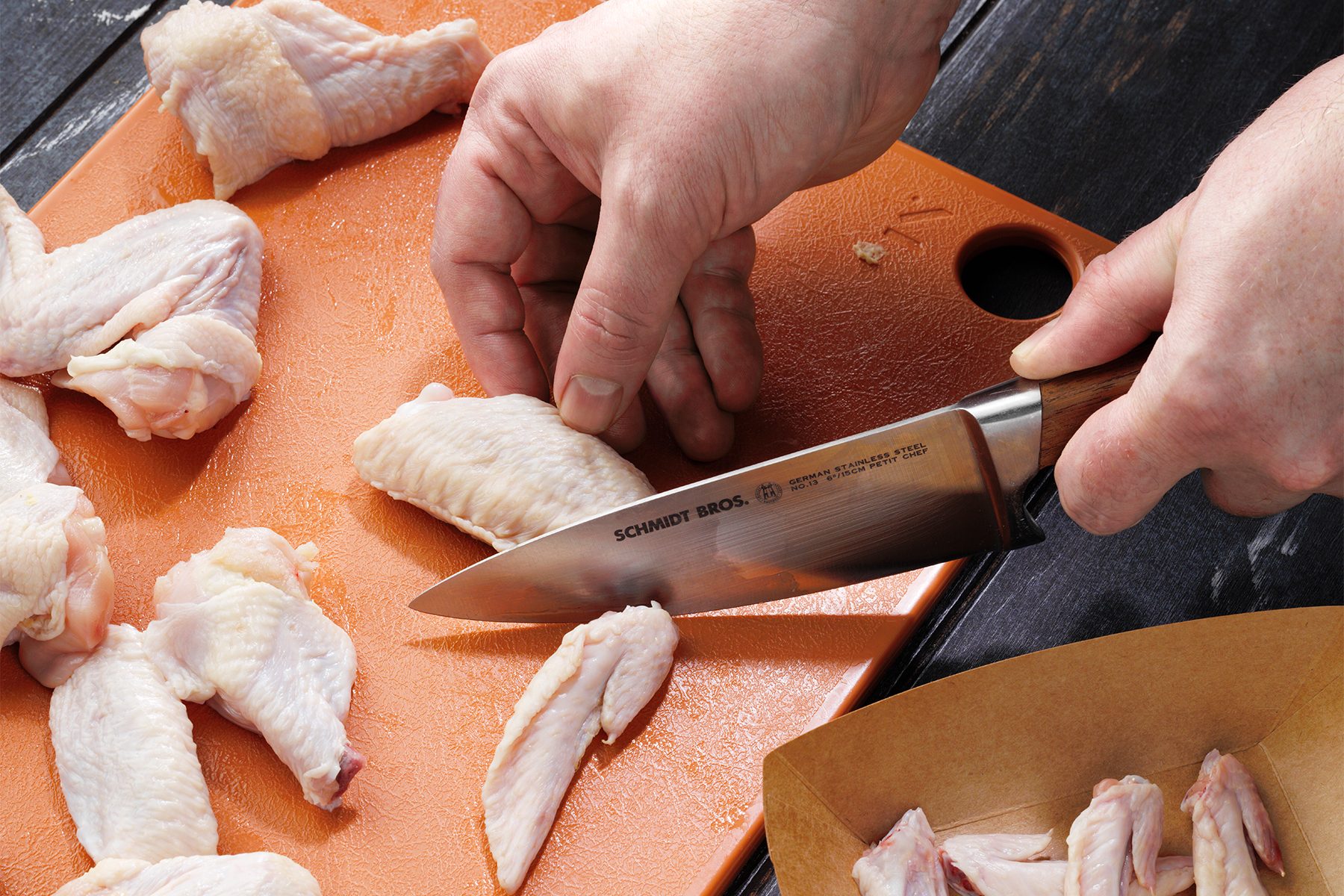 A person cutting Chicken wings With Knife