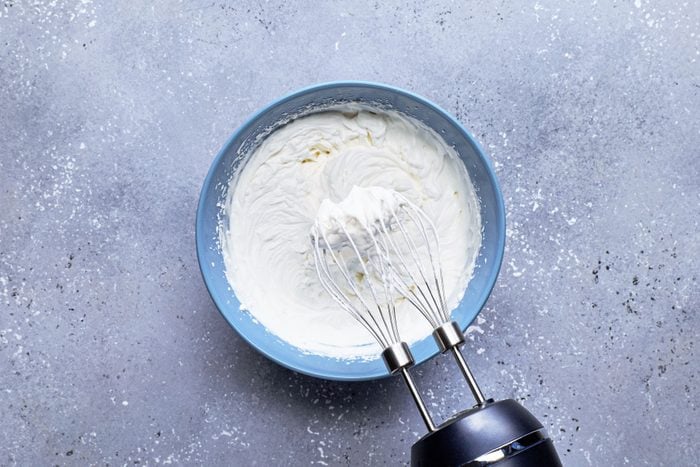 whipping cream in a large bowl with hand mixer