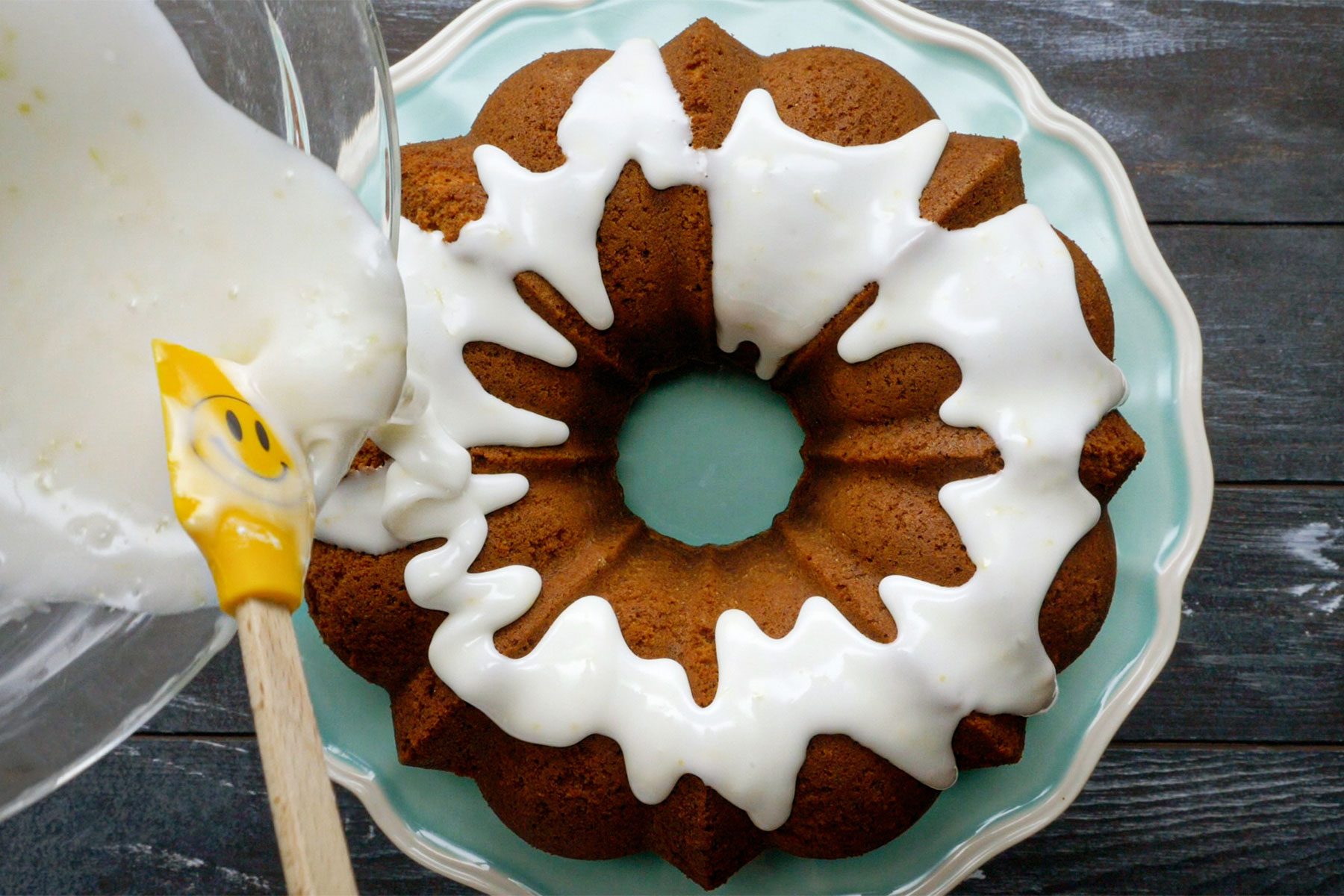 Overhead shot of 7UP pound cake dressing; in a small bowl, mix confectioners' sugar, lemon juice and enough 7UP to reach desired consistency; drizzle over cake; dark wooden background;