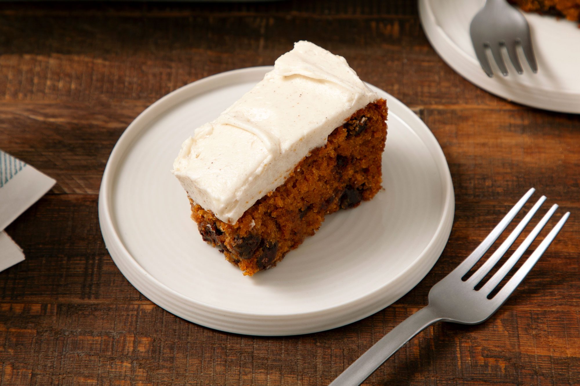 Close shot of pumpkin bar served on a small plate with fork on wooden surface