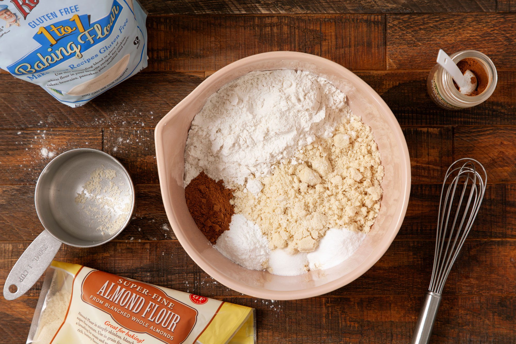 overhead shot of gluten-free flour, almond flour, pumpkin pie spice, baking soda, baking powder and salt in a large bowl on wooden surface
