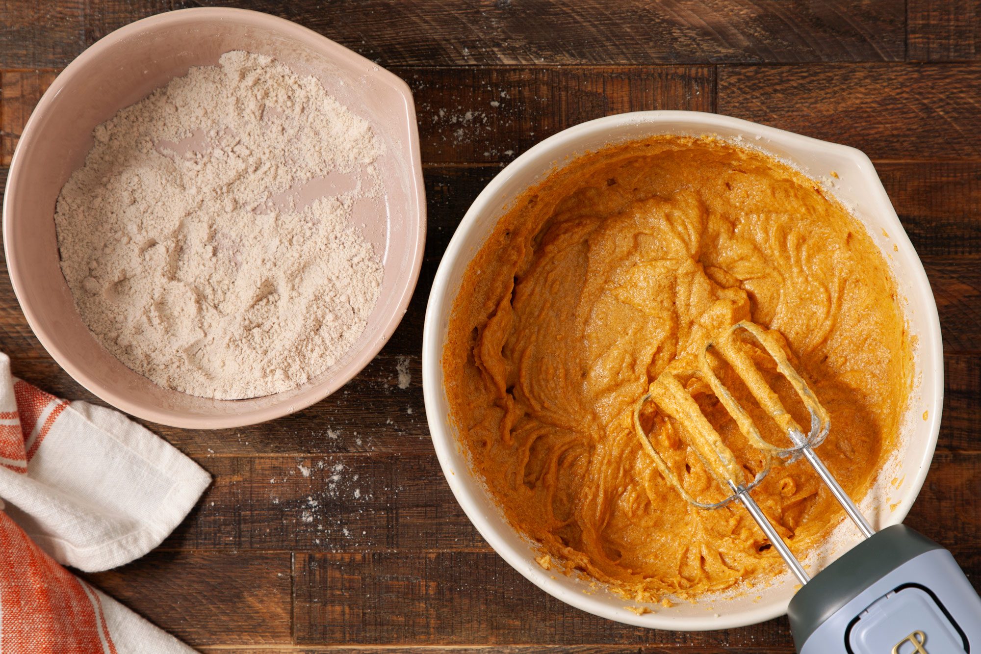 overhead shot of mixing Pumpkin Bars batter using hand mixer in a large bowl on wooden surface