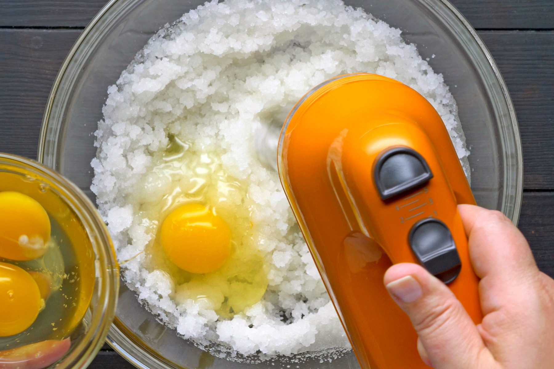 A hand beating eggs with the mixture of other ingredients in a bowl