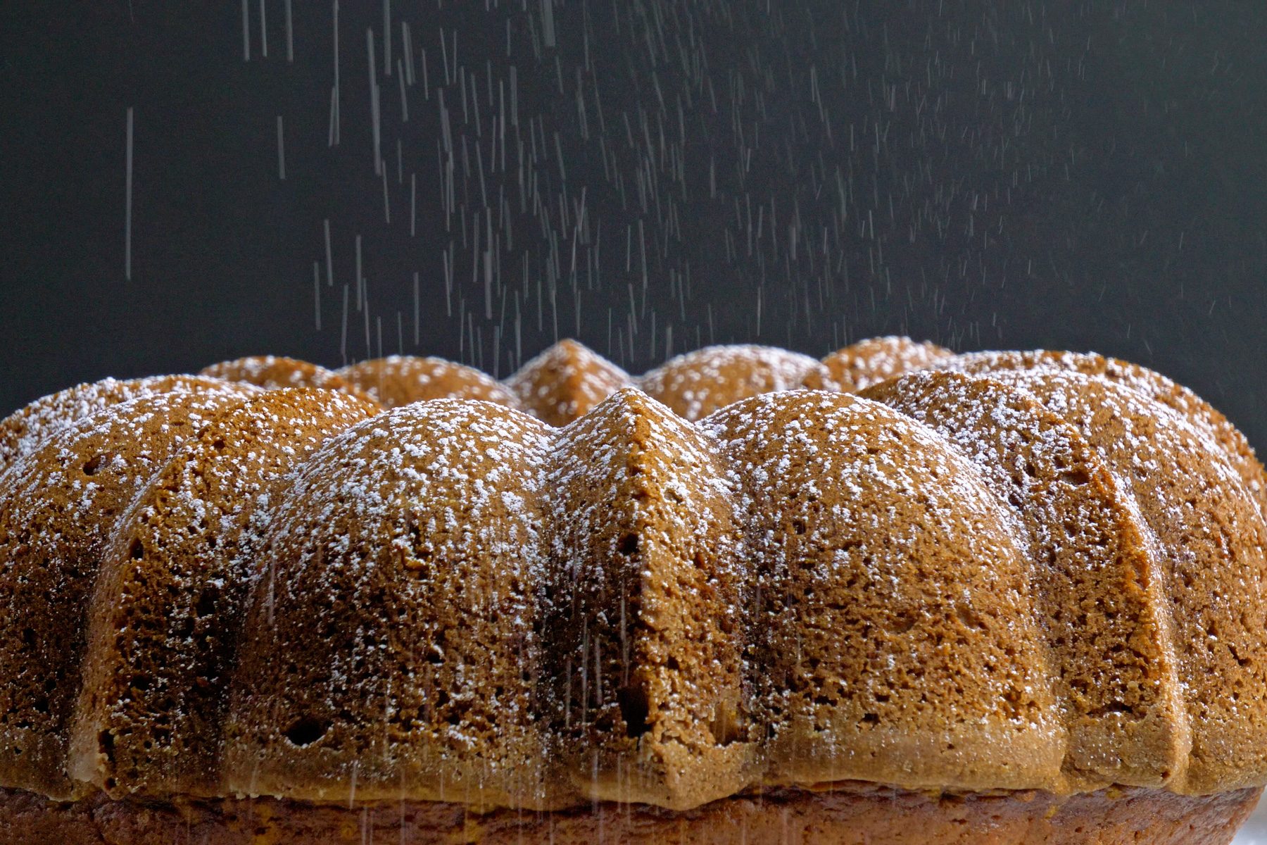 A pumpkin bundt cake with confectioners sugar dust topping