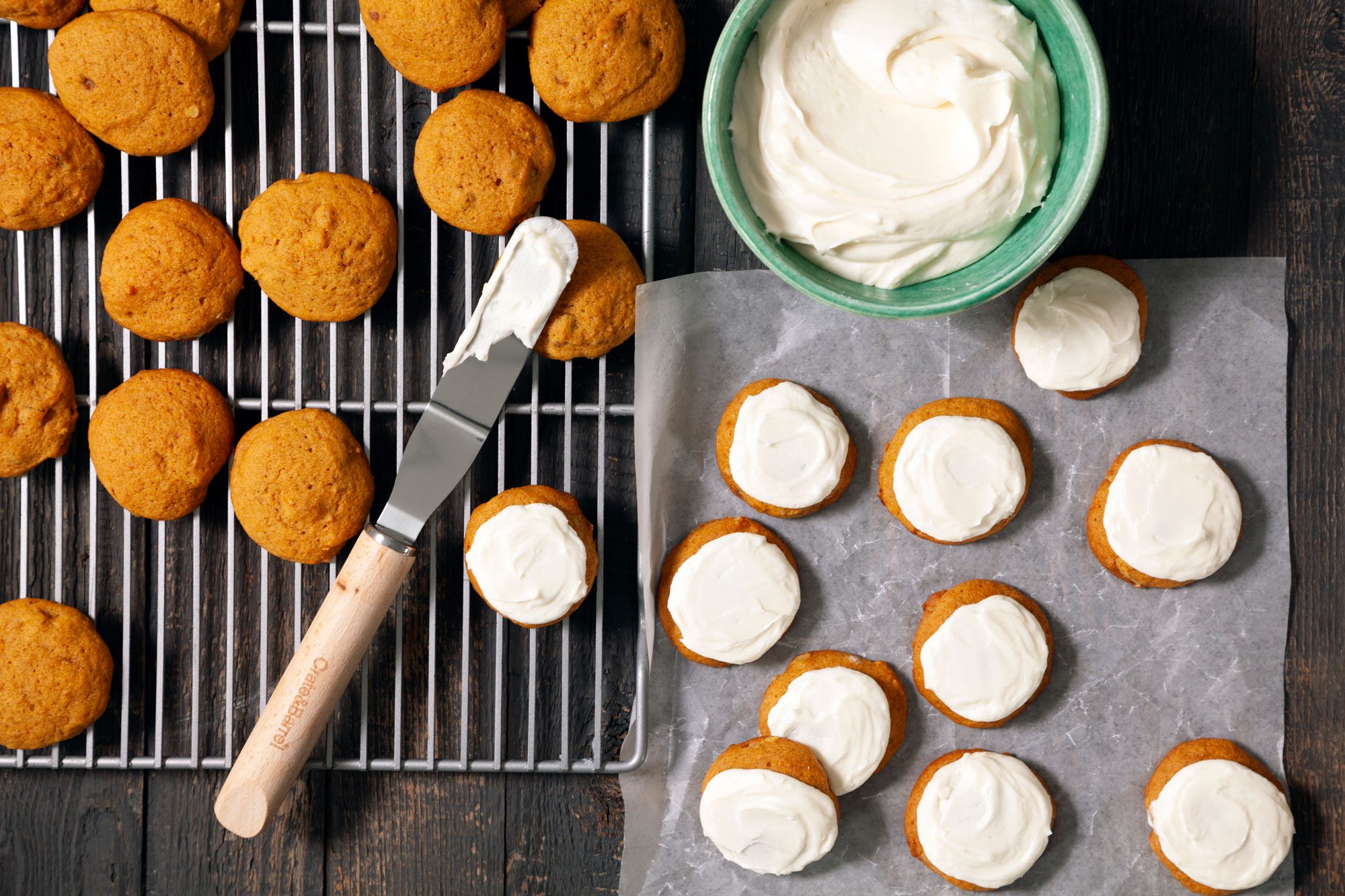 Pumpkin Cookies with a knife on wire rack; Pumpkin Cookies With Cream Cheese Frosting on baking paper on wooden surface