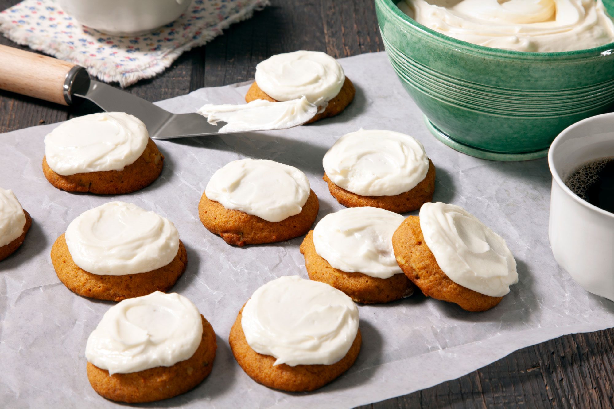 Pumpkin Cookies With Cream Cheese Frosting on baking paper on wooden surface